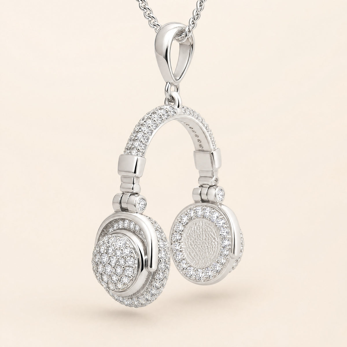 Pavé headphone pendant at an angle, showing the domed pavé outer cap and the textured ear pad ringed with stones