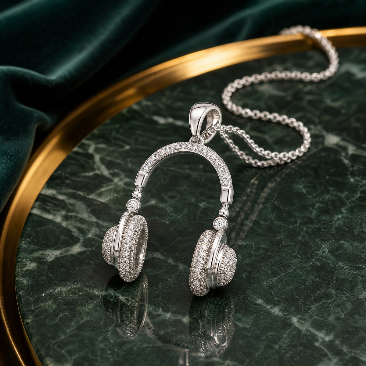 Pavé headphone pendant in sterling silver standing on green marble, chain trailing