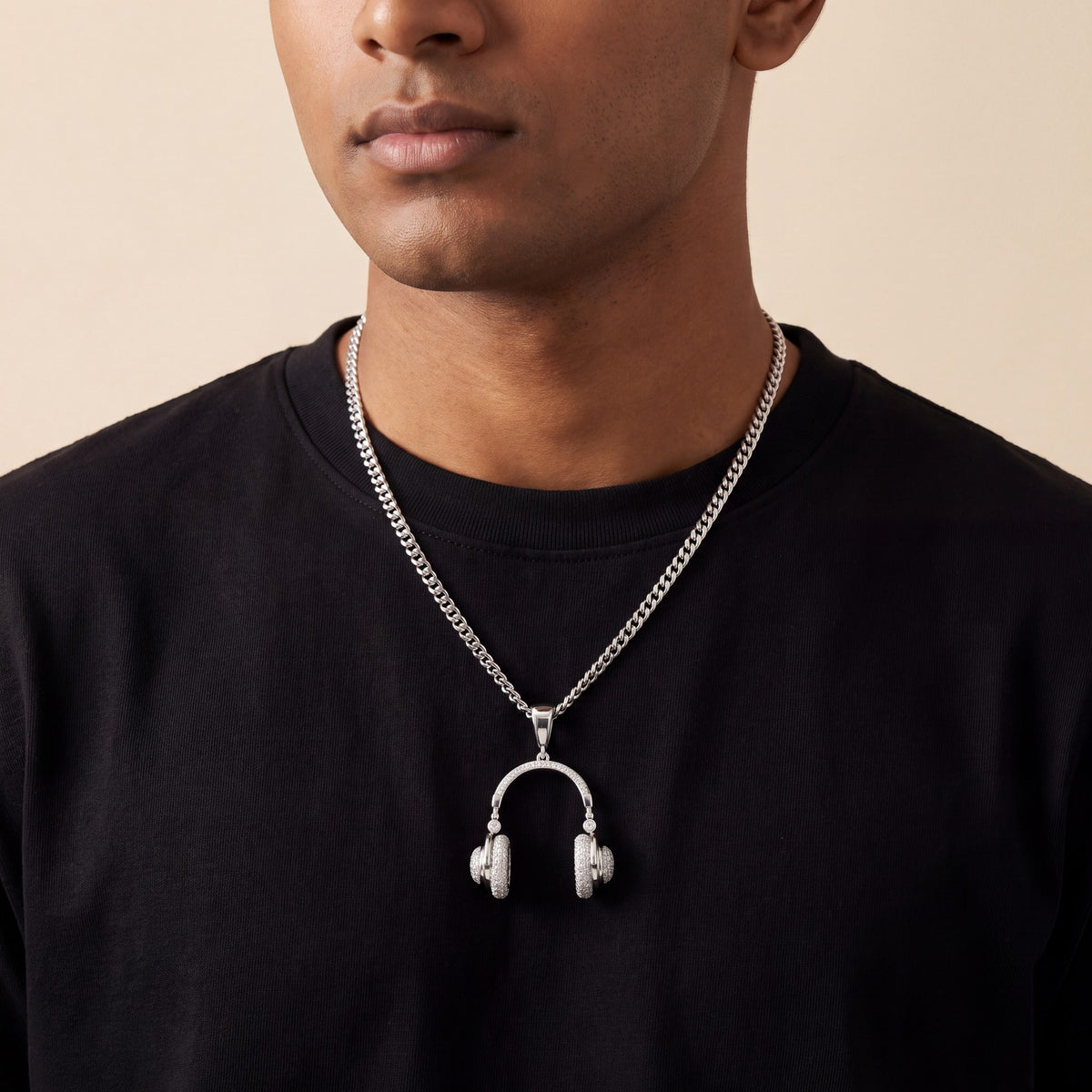 Pavé headphone pendant worn on a silver chain over a black crew-neck tee